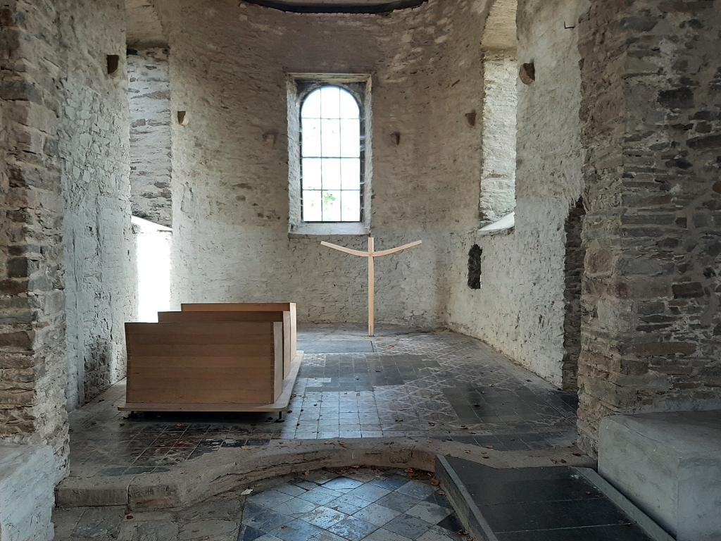Kapelle mit vier Holzbänken und einem Kreuz   