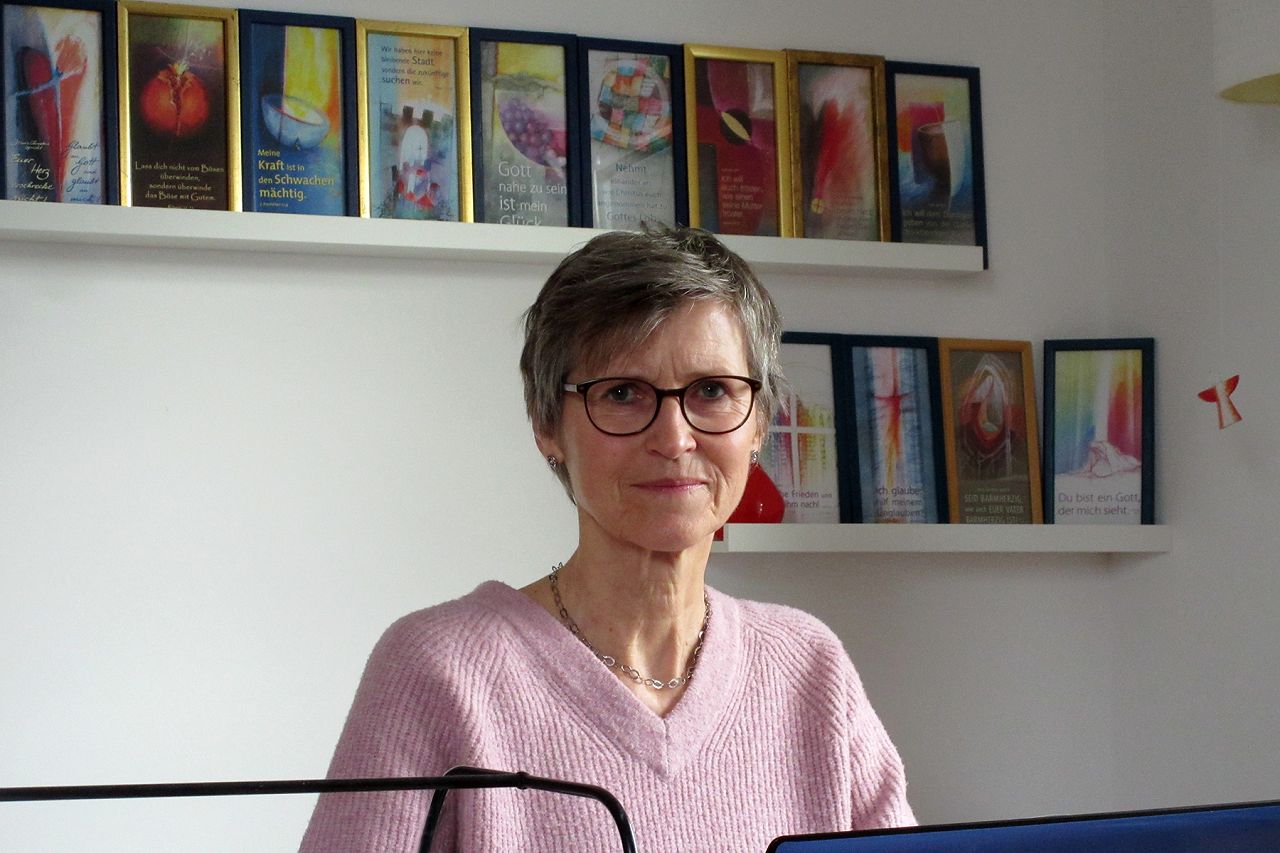 Das Foto zeigt Renate Karnstein vor einer Wand mit früheren Jahreslosungen 